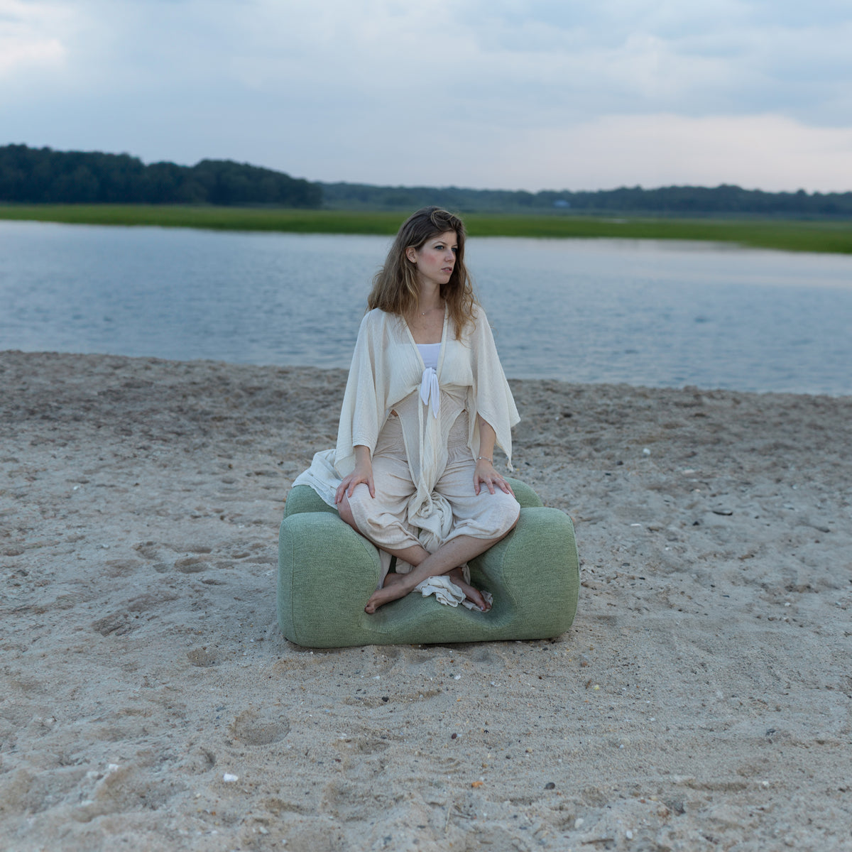 A person sitting on the Oyster Meditation Chair at the beach
